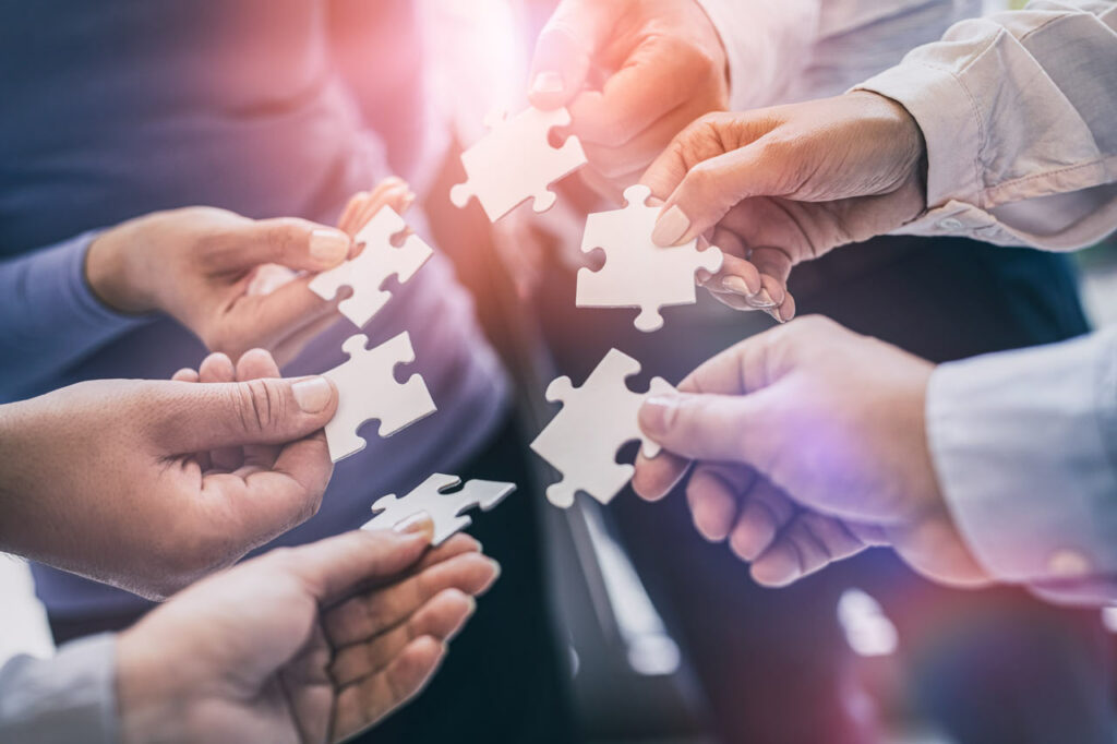 Hands connecting puzzle pieces representing teamwork and core values at Cooach Group, offering corporate finance solutions in Spain and Sweden.